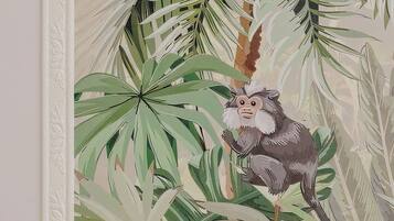 Une œuvre d’art encadrée représentant un singe au milieu d’une végétation tropicale.