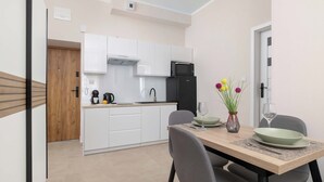 A modern kitchen with white cabinets, a black refrigerator, a microwave, and a coffee maker. - Cosy Apartment for 4 People | Coffee Machine (Bielsko-Biała)