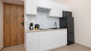 A compact kitchen with white cabinets, a black refrigerator, a coffee maker, and a kettle. - Cosy Apartment for 4 People | Coffee Machine (Bielsko-Biała)