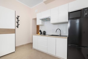 A modern kitchen with white cabinetry, a black refrigerator, and a coffee maker on the counter. - Cosy Apartment for 4 People | Coffee Machine (Bielsko-Biała)