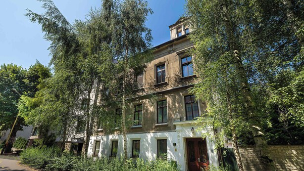 Un immeuble à plusieurs étages, de style architectural traditionnel, avec une entrée centrale et une porte ainsi que des fenêtres au rez-de-chaussée.