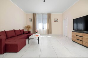 Una sala de estar con un sofá seccional, una mesa de centro, un televisor y una puerta.