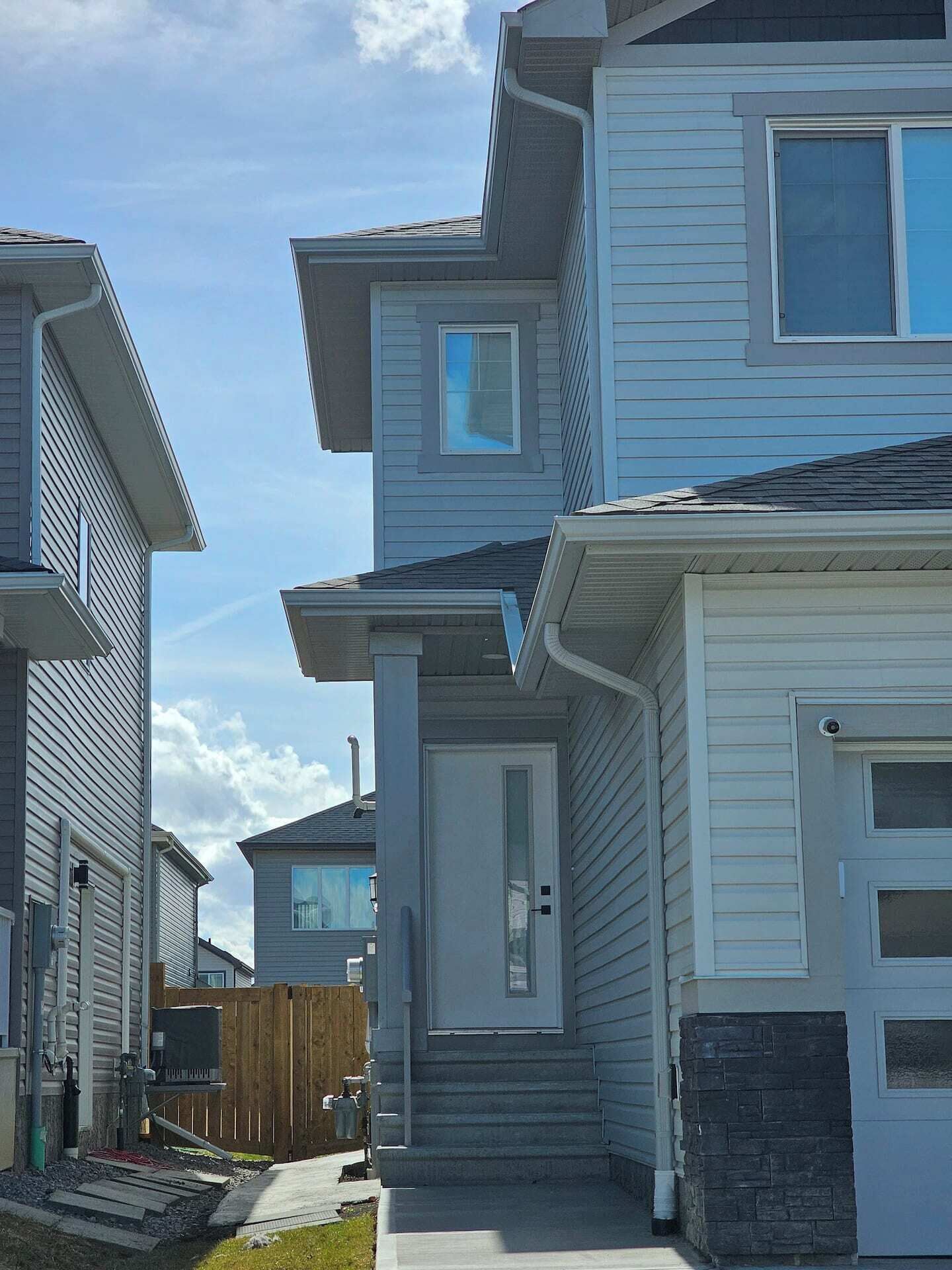 Um bairro residencial com várias casas de dois andares, cada uma com porta de entrada e garagem.