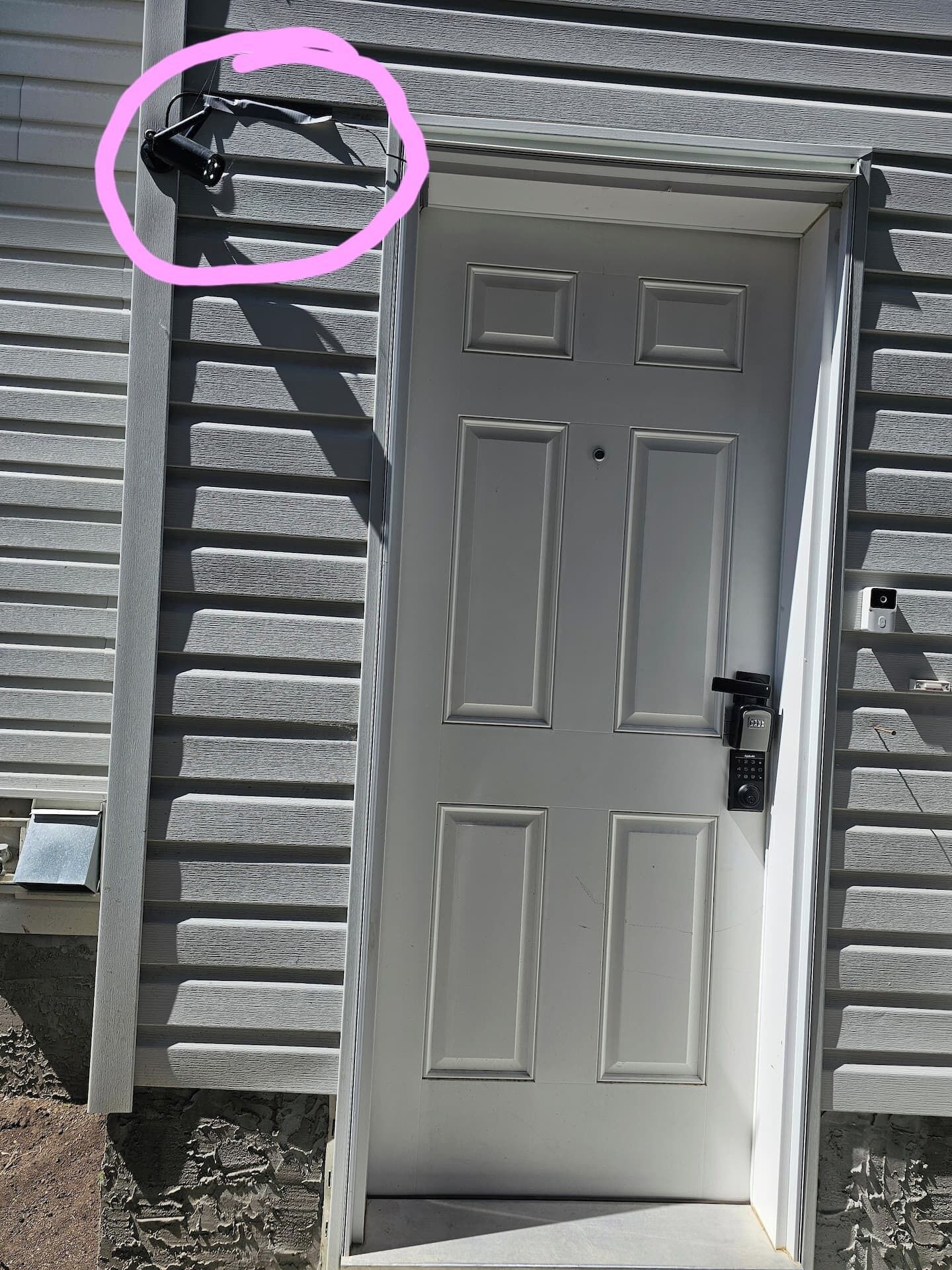 A white door with a keypad lock and a small mailbox to the left.