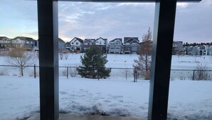 A covered outdoor area with a view of a residential neighborhood during winter. - SwitHome Cher Cozy Studio: Pond View, Near YEG Airport (Edmonton)