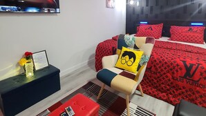 A modern bedroom with a bed, a TV, a red and black patterned headboard, and a red and black themed decor. - SwitHome Cher Cozy Studio: Pond View, Near YEG Airport (Edmonton)
