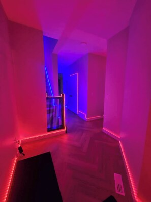 Ein Flur mit Wandbeleuchtung durch LED-Streifen und Holzboden.