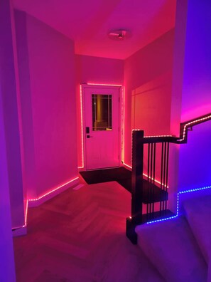 A hallway with a staircase, white walls, and pink lighting. - SwitHome Properties Glen Near Yeg Airport | 3 beds 2.5 baths with Double Garage (Edmonton)
