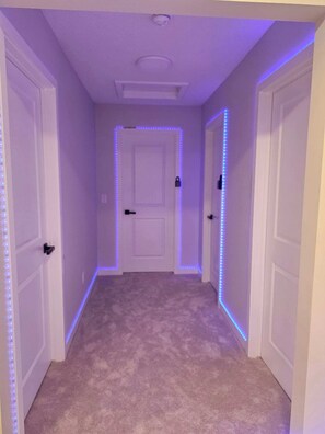 A hallway with carpeted floors and white doors, illuminated by blue LED strip lights along the edges. - SwitHome Properties Glen Near Yeg Airport | 3 beds 2.5 baths with Double Garage (Edmonton)