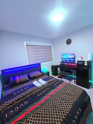 Ein Schlafzimmer mit einem Bett, einem Schreibtisch, einem Computer und einem Fernseher.