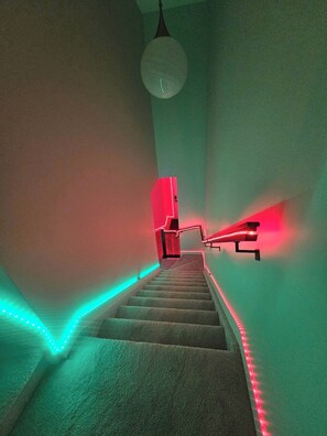 Eine Treppe mit LED-Beleuchtung am Rand, einem Geländer und einer Leuchte oben.