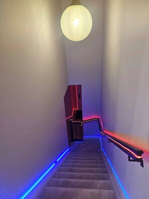 Eine Treppe mit LED-Beleuchtung entlang der Kanten und einer Hängeleuchte.