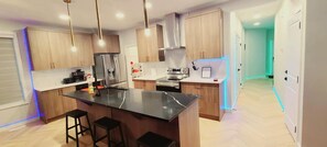 A modern kitchen with wooden cabinets, stainless steel appliances, and a central island with stools. - SwitHome Properties Glen Near Yeg Airport | 5 beds 2.5 baths with Double Garage (Edmonton)