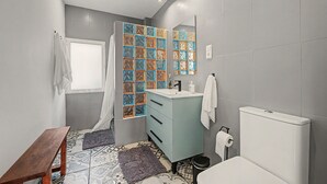 Un baño con ventana, lavabo, inodoro y espejo.