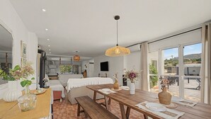 Una habitación amplia con una mesa de comedor de madera, un sofá y un gran ventanal con vistas al exterior.