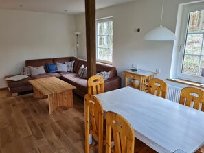 Una sala moderna con un sofá de cuero marrón, una mesa de centro de madera y sillas a juego.