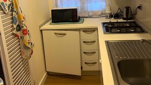 Une cuisine de taille réduite équipée d’un four à micro-ondes, d’une cuisinière et d’un évier.