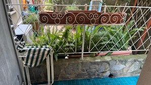Un petit espace extérieur doté d’un sol carrelé bleu, d’un portail en métal et d’une chaise avec un coussin à rayures.