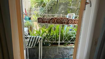 Une pièce donnant sur une terrasse bleue ornée de carreaux, une porte en métal et une chaise avec un coussin à rayures.