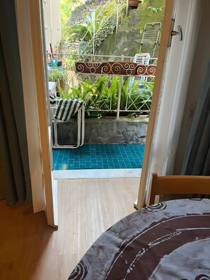 A room with a view of a blue tiled patio, a metal gate, and a chair with a striped cushion. - Casa Baba Apartment – Great Location in Rapallo, Ligurian Riviera (Rapallo)