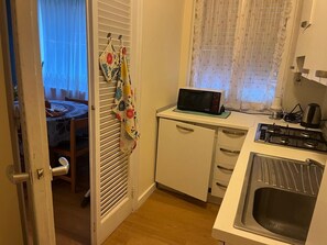 A compact kitchen with a microwave, sink, and a window with sheer curtains. - Casa Baba Apartment – Great Location in Rapallo, Ligurian Riviera (Rapallo)