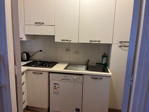 A compact kitchen with a gas stove, a dishwasher, and a sink. - Casa Baba Apartment – Great Location in Rapallo, Ligurian Riviera (Rapallo)