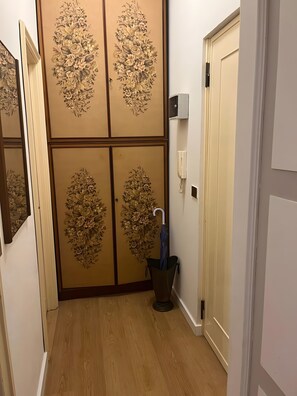 Ein Flur mit Holzboden, einer Tür mit floralem Dekor und einem an der Wand befestigten Telefon.