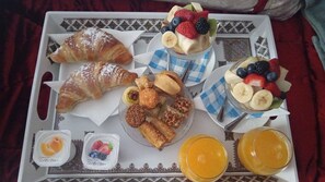 A tray with croissants, fruit, nuts, and juice.