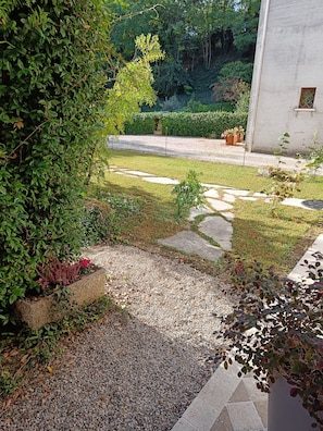 Ein Garten mit Kiesweg, Steinmauer und verschiedenen Pflanzen.
