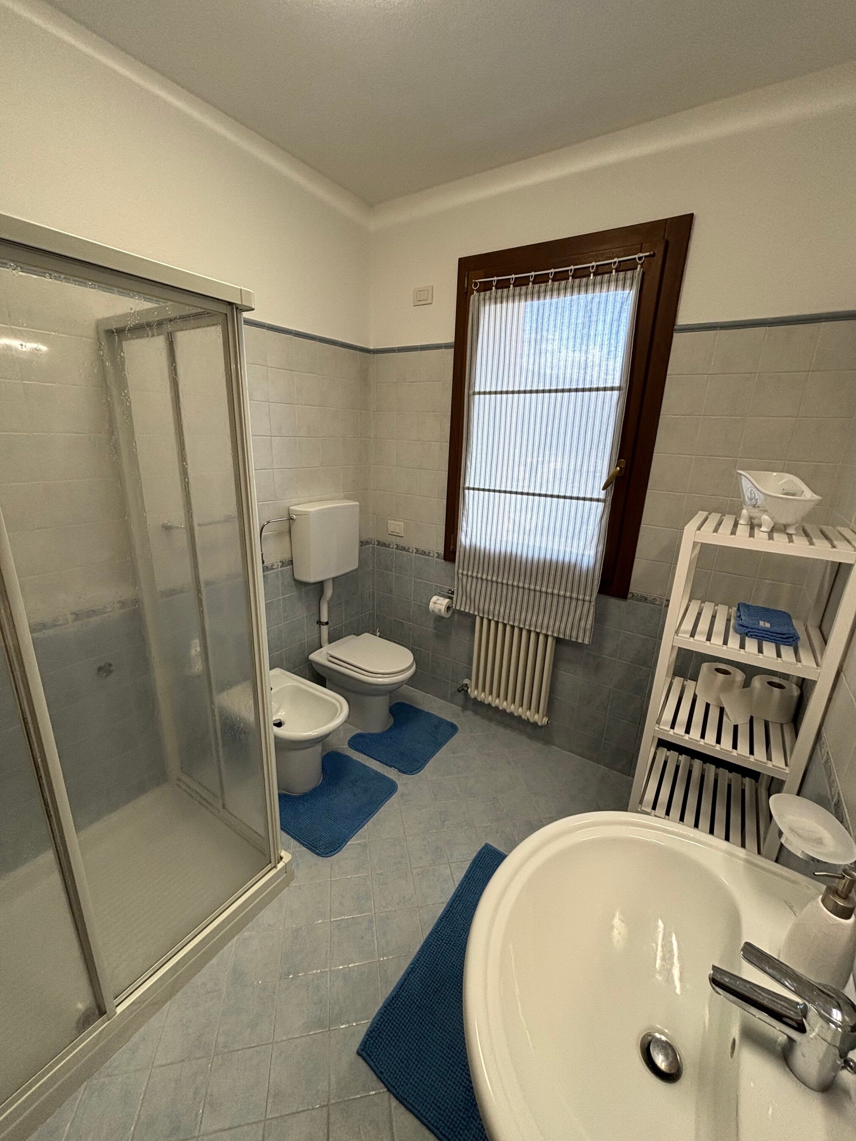 Une salle de bain comprenant une douche à parois de verre, des toilettes, un bidet, un lavabo et un porte-serviettes.