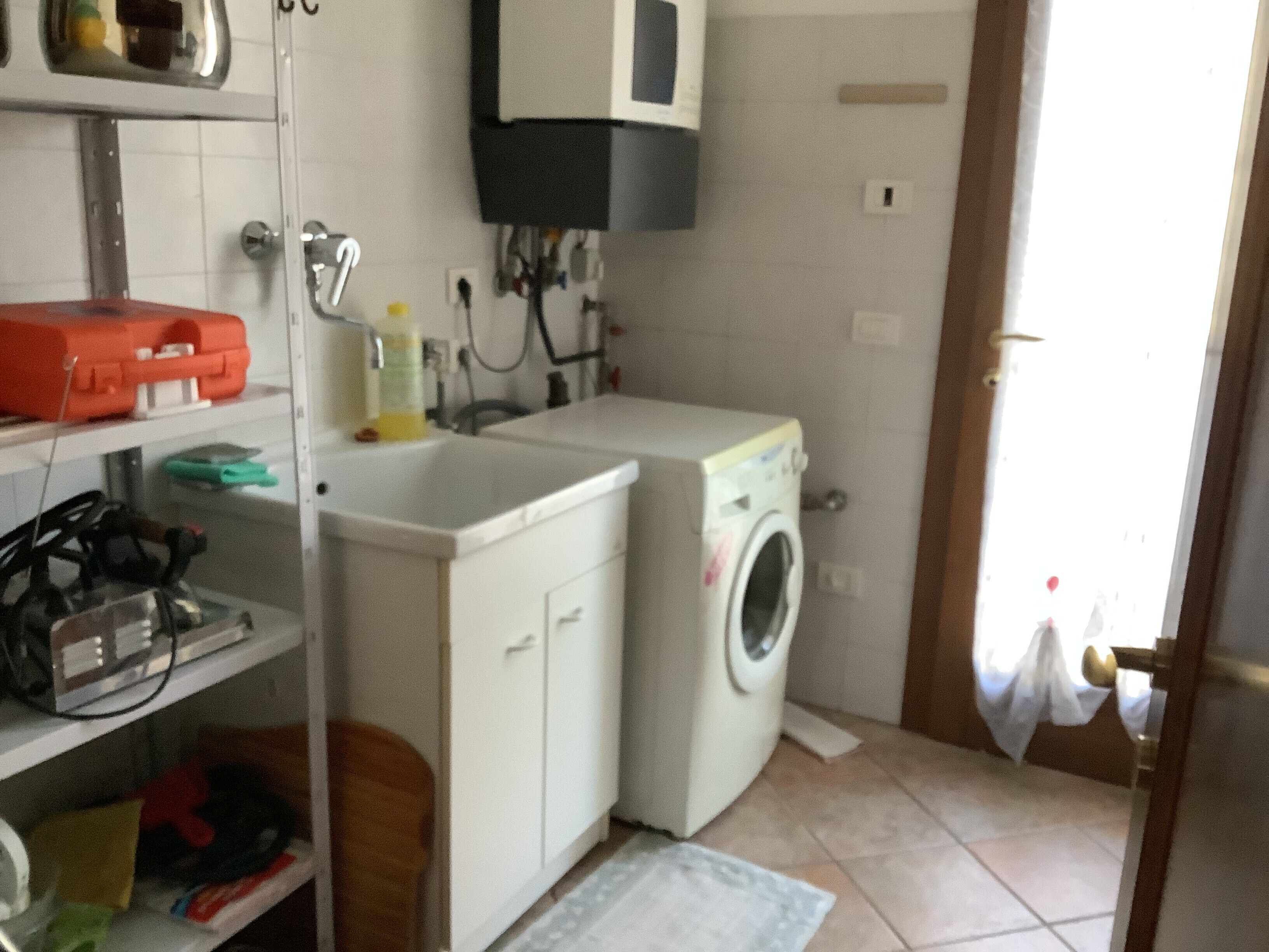 Una lavanderia con lavatrice, asciugatrice e scaffali con diversi oggetti.