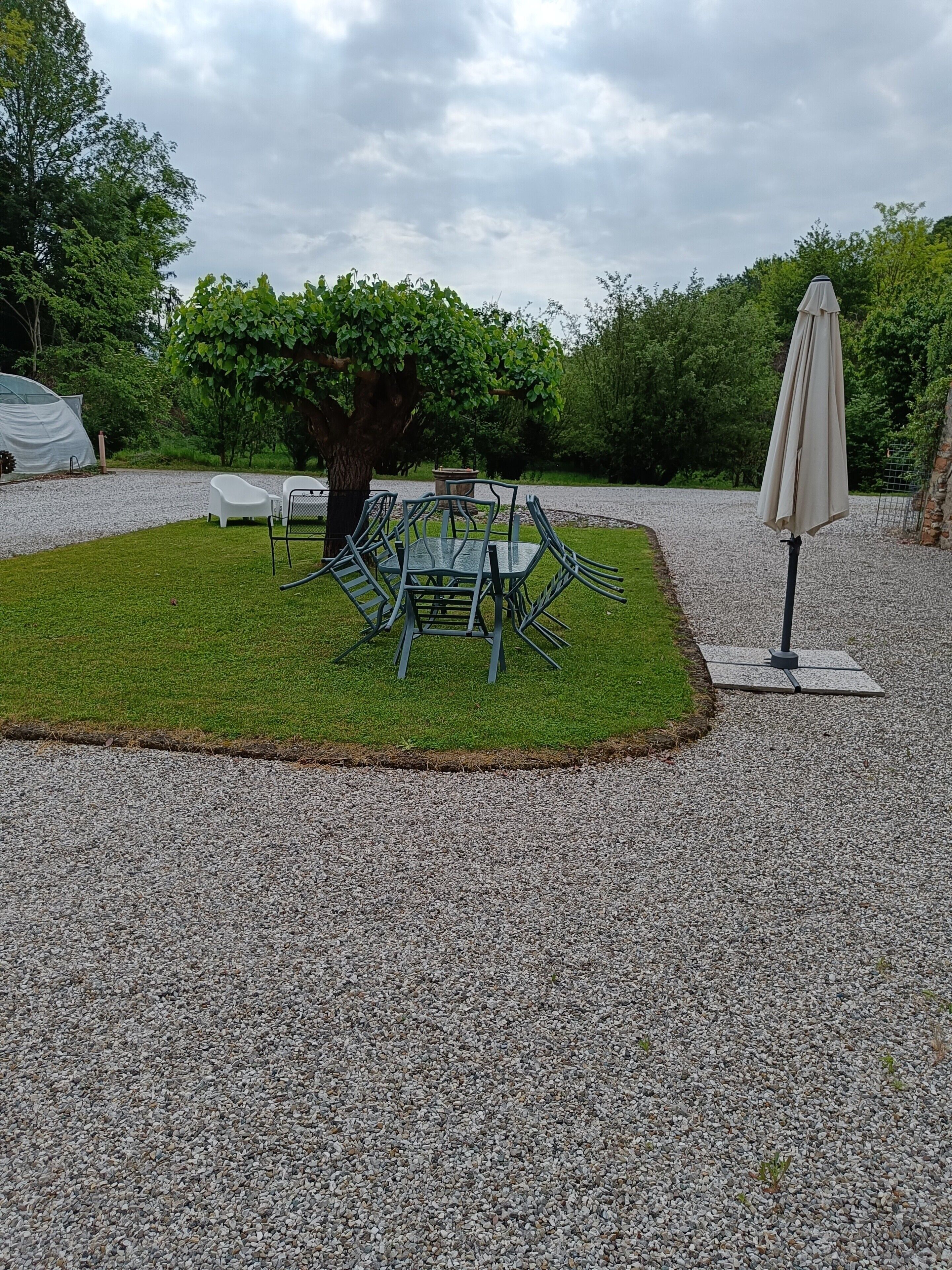 Ein Garten mit Tisch und Stühlen, umgeben von einem Kiesweg und viel Grün.