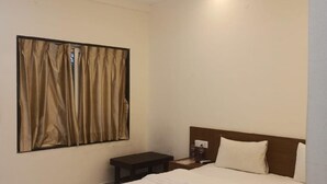 A bedroom with a bed, a nightstand, a ceiling fan, and a window with curtains.