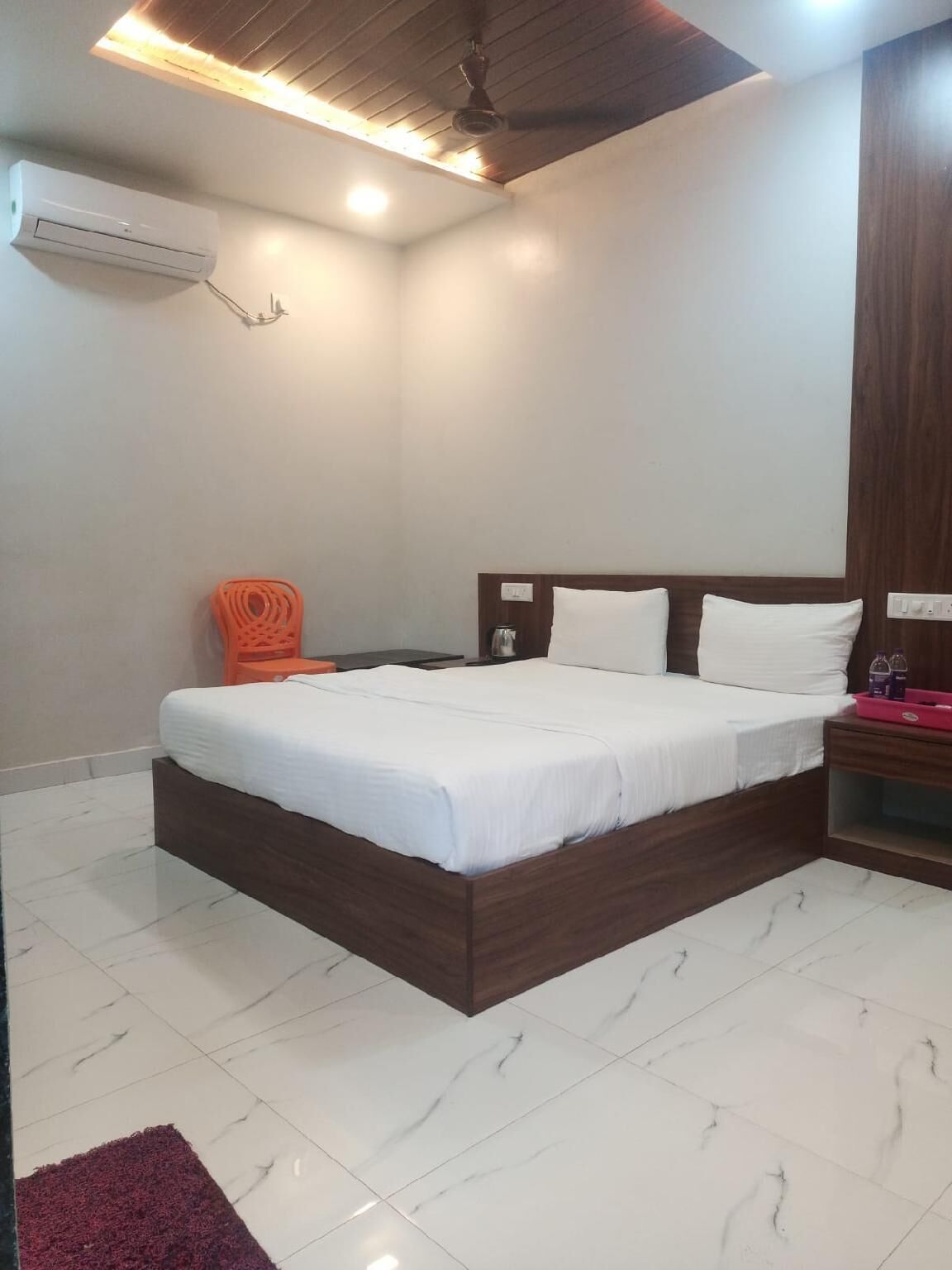 A bedroom with a bed, a nightstand, a chair, and a ceiling fan.