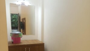 A narrow hallway with a wooden cabinet and a mirror on the wall. - Seashell Retreat (Shrivardhan)