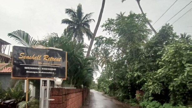 A sign for Seashall Retreat with contact numbers and location in Divegar, Maharashtra. - Seashell Retreat (Shrivardhan)