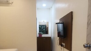 A hotel room with a bed, a television mounted on the wall, and a marble floor. - Seashell Retreat (Shrivardhan)