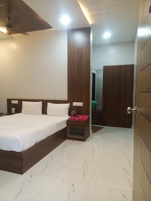 Ein Hotelzimmer mit einem Bett, einem Nachttisch, einem Holzschrank und einem durch eine offene Tür einsehbaren Badezimmer.