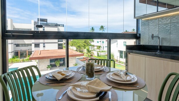 Comedor con una mesa lista para cuatro personas, con vista a una zona residencial con edificios y cielo despejado.