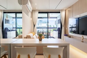 Une cuisine moderne avec un coin repas, de grandes fenêtres et un téléviseur à écran plat.