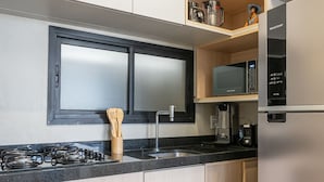 Cocina moderna con horno integrado, microondas y refrigerador de acero inoxidable.