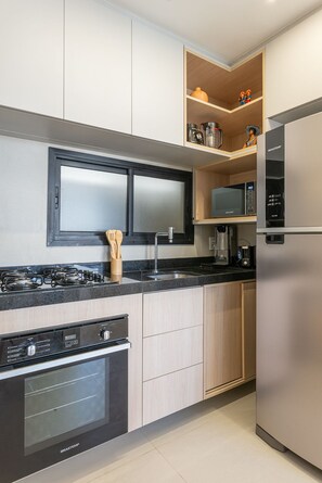 Eine moderne Küche mit eingebautem Backofen, Mikrowelle und einem Edelstahl-Kühlschrank.