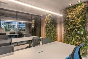 Une salle de conférence avec une longue table, des chaises et un mur recouvert de verdure.