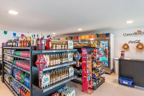 A convenience store with shelves stocked with beverages, snacks, and a refrigerated section. - Experiência Exclusiva em Muro Alto  (N. Sra. do Ó)