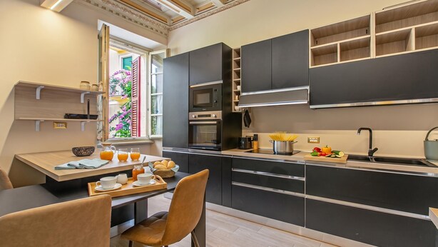 Una cocina moderna con electrodomésticos integrados, un comedor con mesa y sillas, y un ventanal con vistas a zonas verdes.