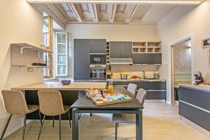 Une cuisine moderne avec un coin repas, comprenant un four encastré, un four à micro-ondes et une machine à café.
