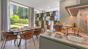 A modern dining area with a table set for breakfast, including bowls of cereal and fruit, and a buffet with pastries. - Boutique Apartment (Toscolano Maderno)