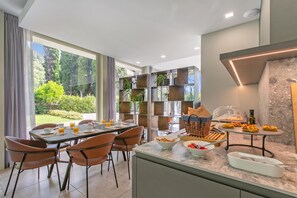 A modern dining area with a table set for breakfast, including bowls of cereal and fruit, and a buffet with pastries. - Boutique Apartment (Toscolano Maderno)