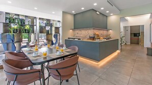 Un comedor moderno con una isla central, asientos y una cocina con salpicadero de piedra.