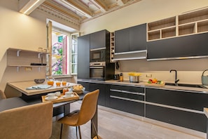 Eine moderne Küche mit integrierten Geräten, ein Essbereich mit Tisch und Stühlen sowie ein Fenster mit Blick auf Grünflächen.